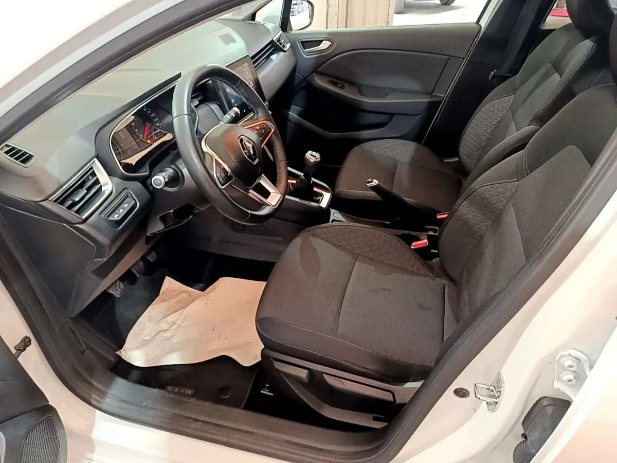 Intérieur avant droit d'une Renault Clio Business TCe 100 blanche, sièges tissu noirs et volant multifonctions cuir.