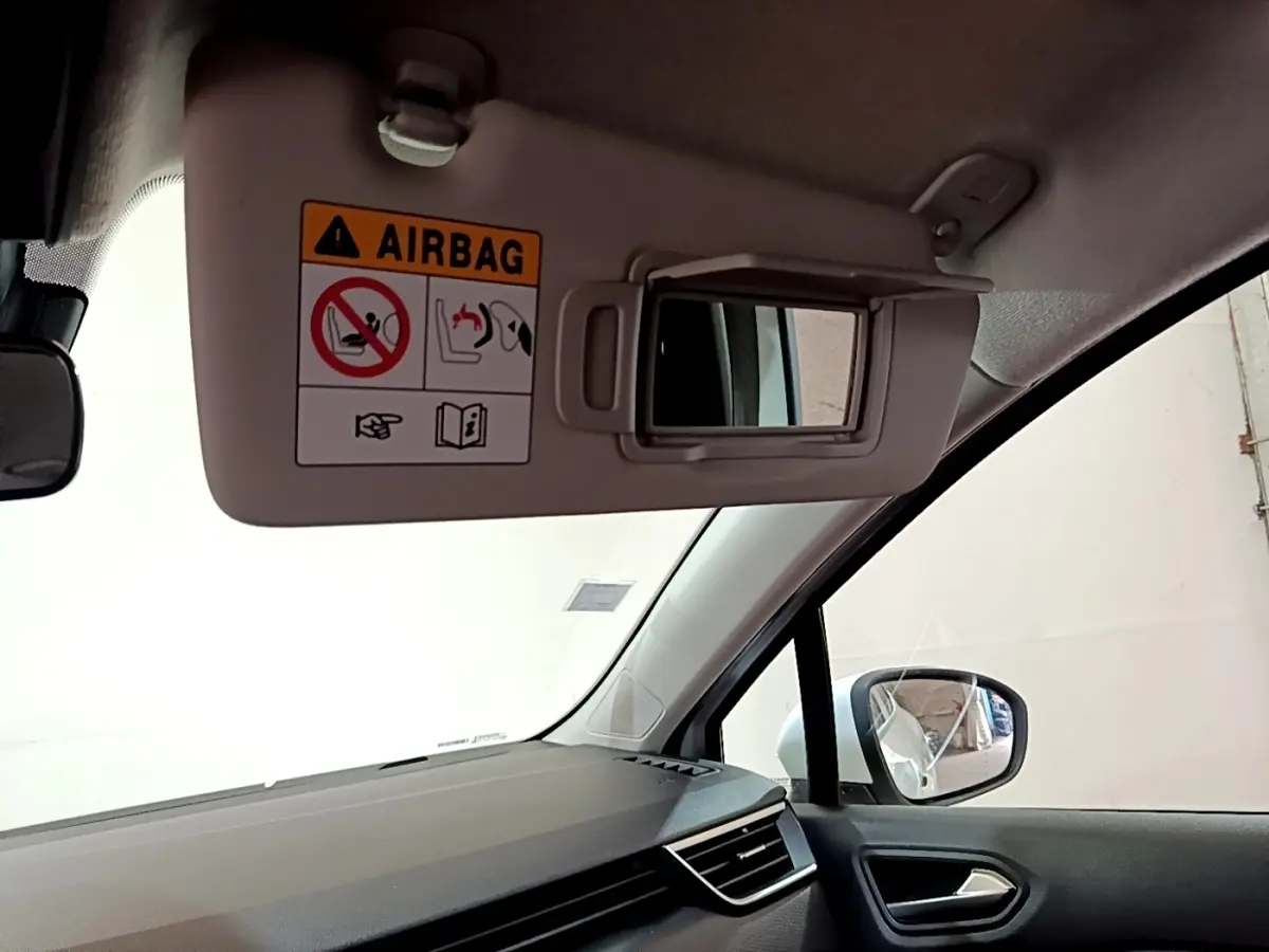 Détail du pare-soleil côté conducteur avec miroir et avertissement airbag dans une Renault Clio Business blanche de 2019.