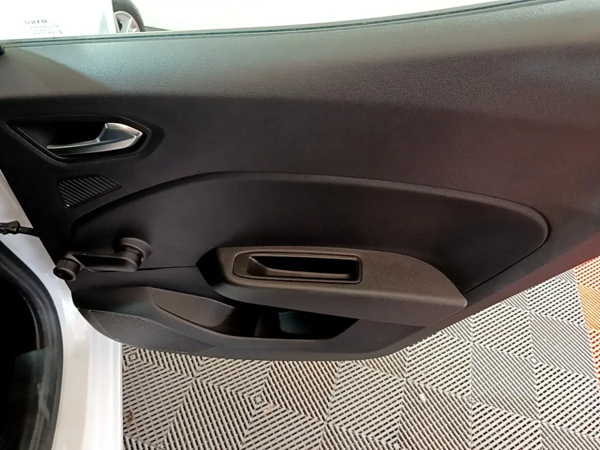 Gros plan sur la porte côté gauche d'une Renault Clio Business blanche, avec poignée manuelle et panneau noir.