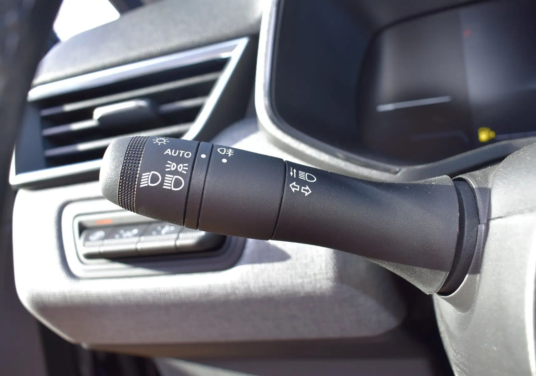 Gros plan sur la commande des phares et clignotants dans l’habitacle de la Renault Clio V TCe 90 noir, côté gauche du volant.