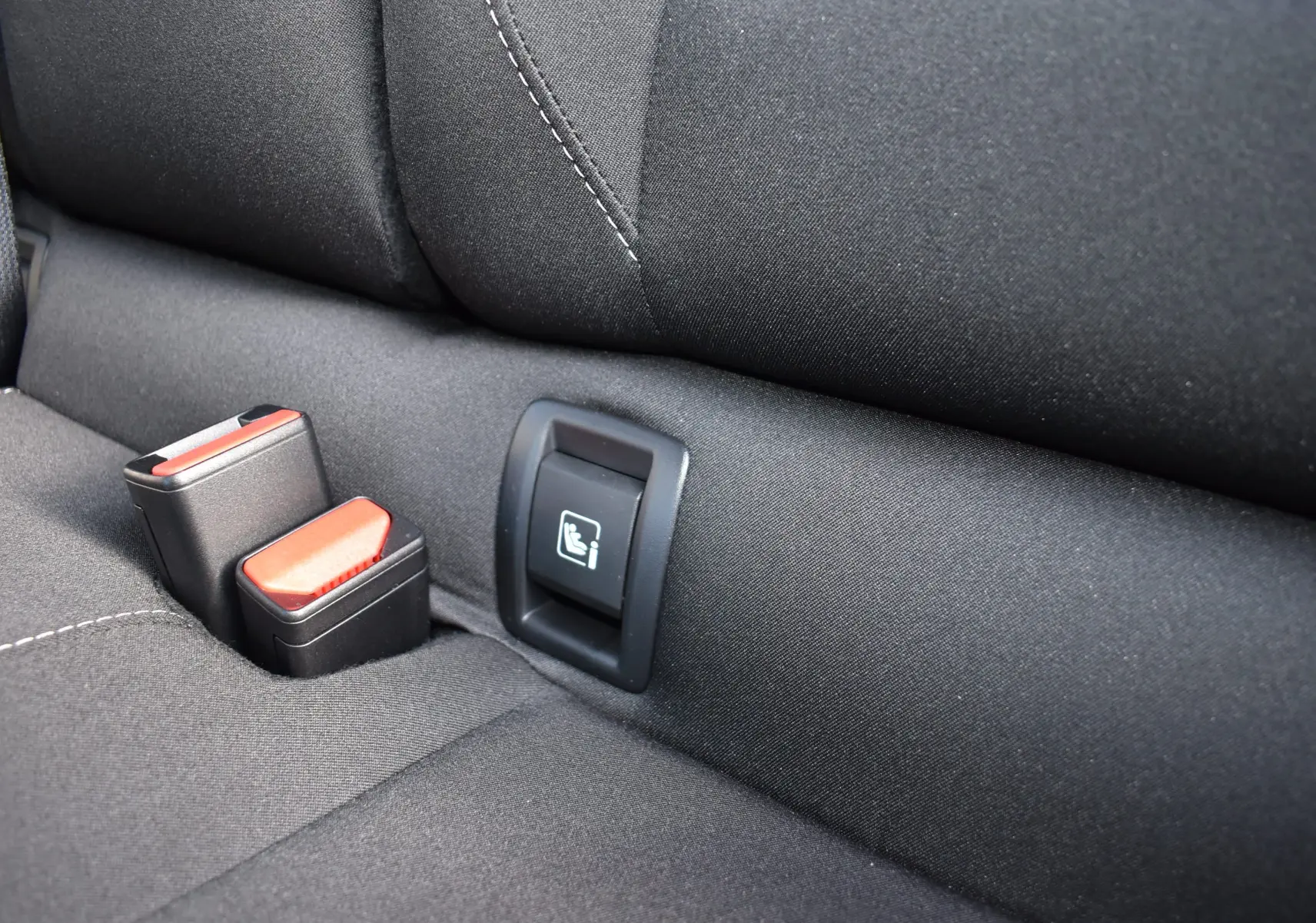 Gros plan sur la banquette arrière noire de la Renault Clio V, montrant les attaches ISOFIX et les boucles de ceinture.