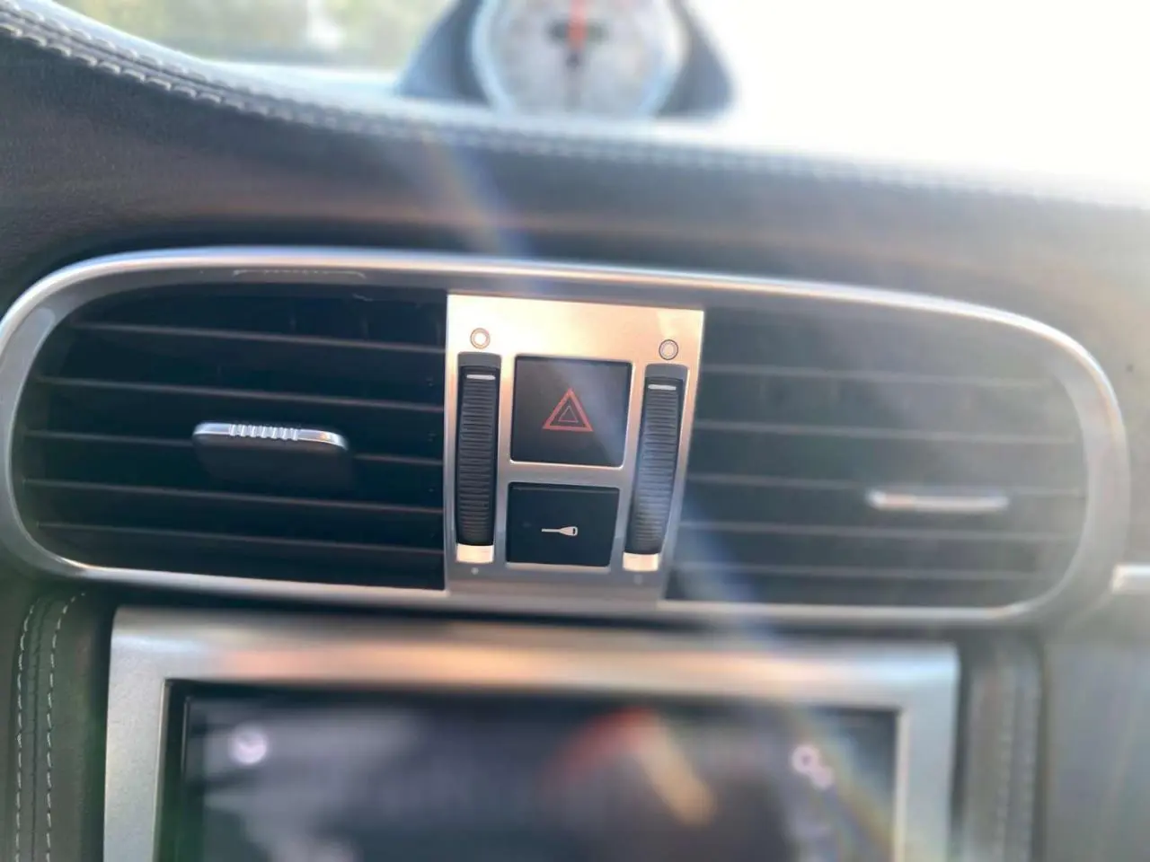 Gros plan sur la console centrale de la Porsche 911 997 Carrera 4S 2007, montrant les aérateurs et commandes d'alerte.