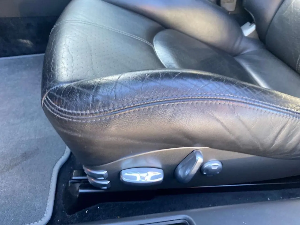 Gros plan sur le siège avant en cuir noir de la Porsche 911 997 Carrera 4S, montrant les commandes électriques latérales.
