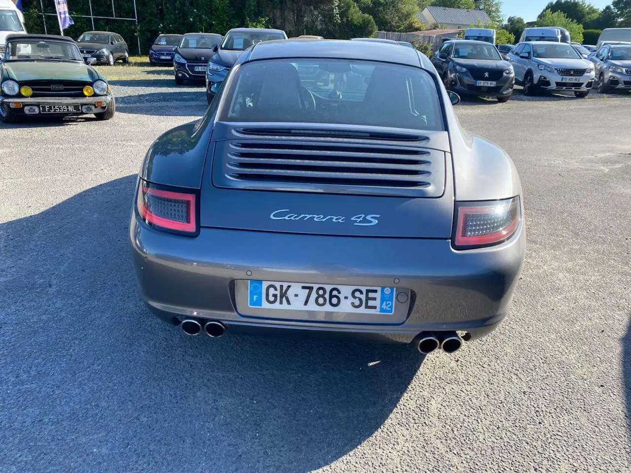 Vue arrière d'une Porsche 911 Carrera 4S 2007 gris météore avec double sortie d'échappement et feux arrière LED.
