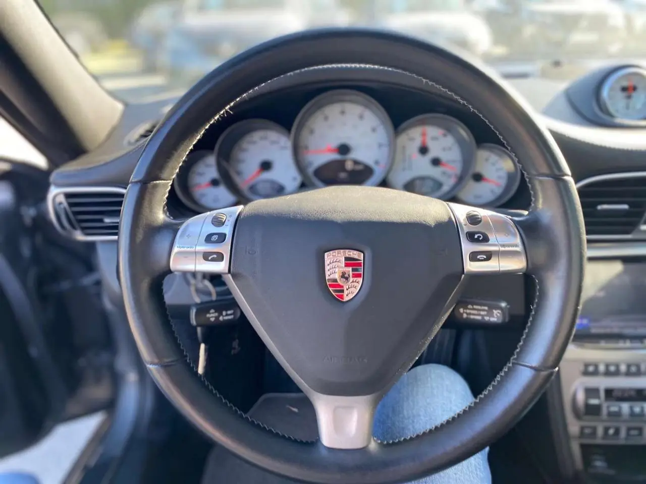 Vue rapprochée du volant en cuir noir avec logo Porsche et compteurs blancs d'une 911 Carrera 4S 2007.