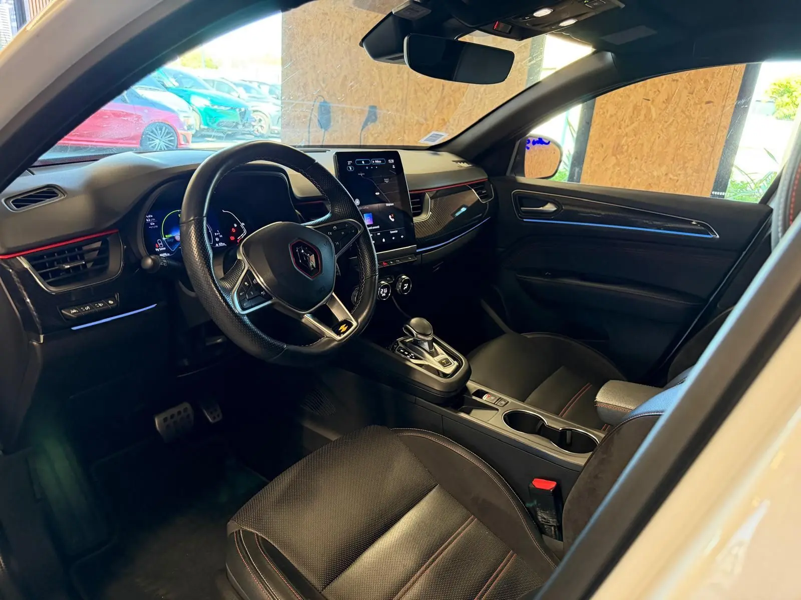 Vue intérieure côté conducteur de la Renault Arkana blanc nacré, volant cuir multifonctions et écran tactile vertical.