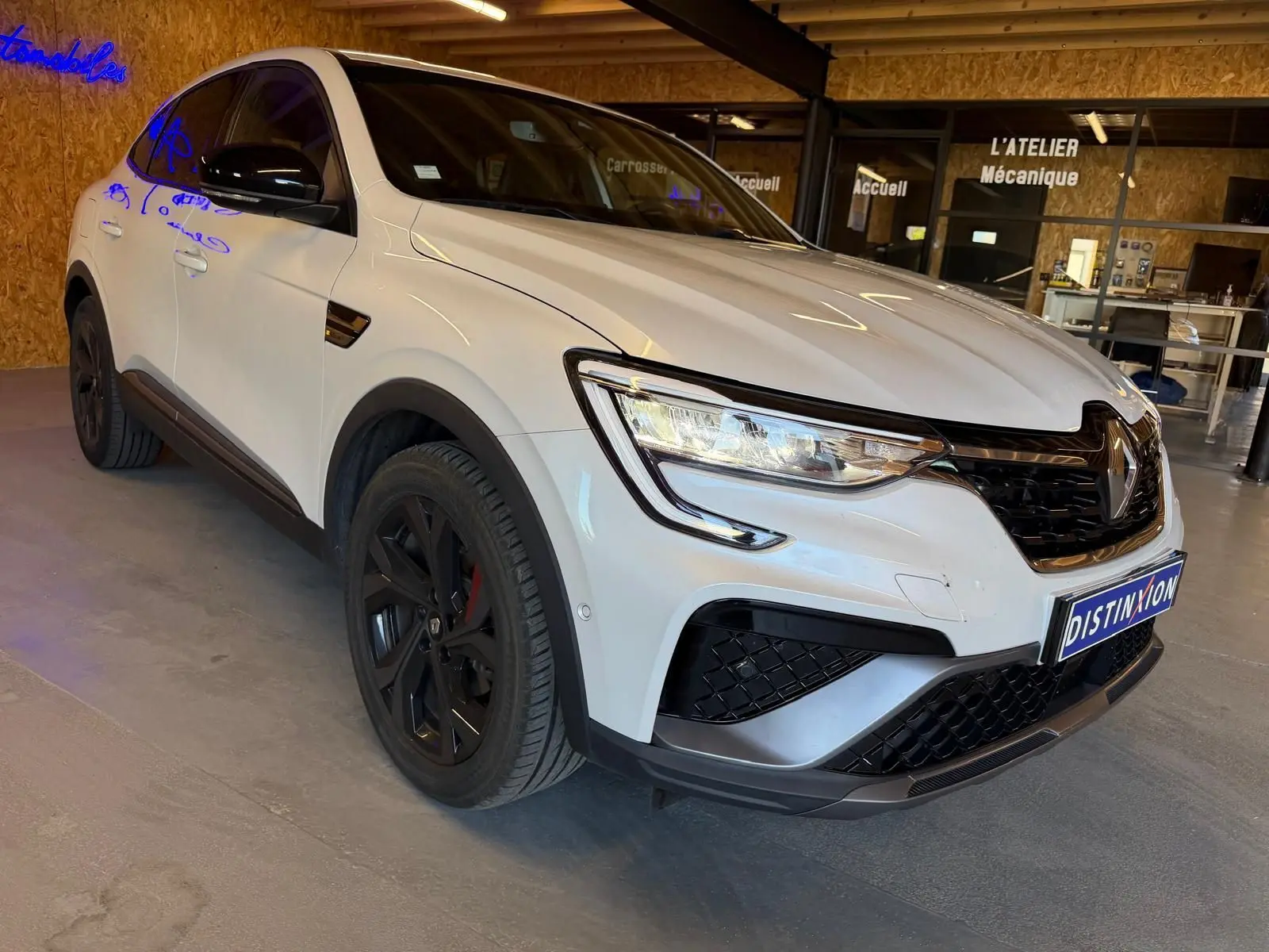 Renault Arkana blanc nacré en 3/4 avant droit, avec jantes noires et calandre noire brillante.