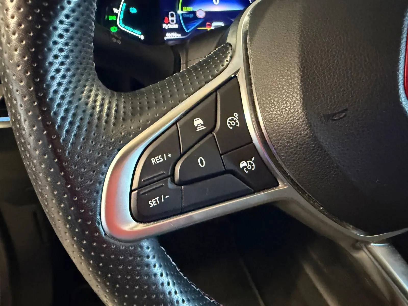 Gros plan sur les commandes multifonctions à gauche du volant cuir perforé du Renault Arkana blanc nacré.