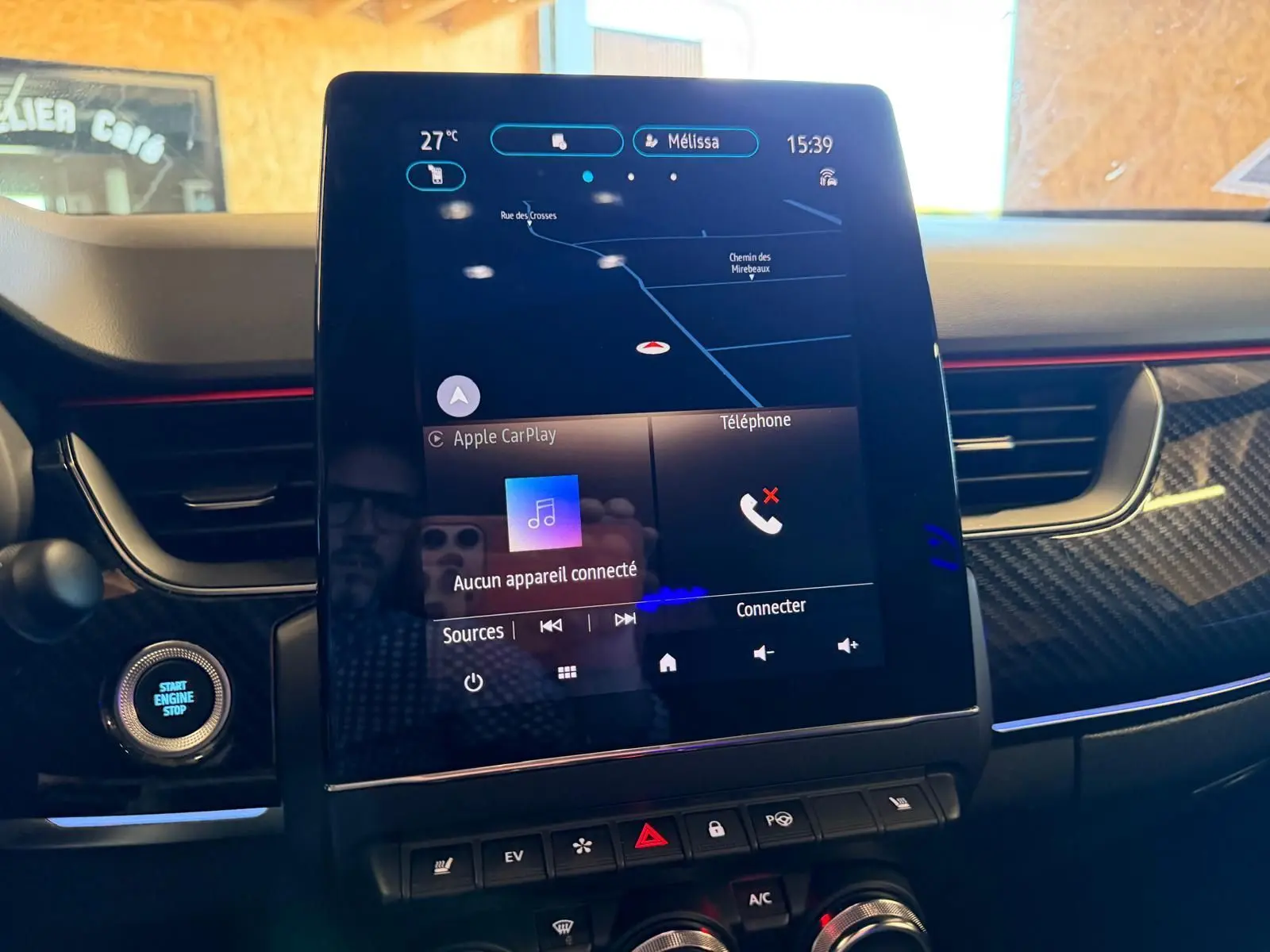 Vue rapprochée de l’écran tactile central du Renault Arkana blanc nacré 2021 avec commandes climatisation et démarrage.