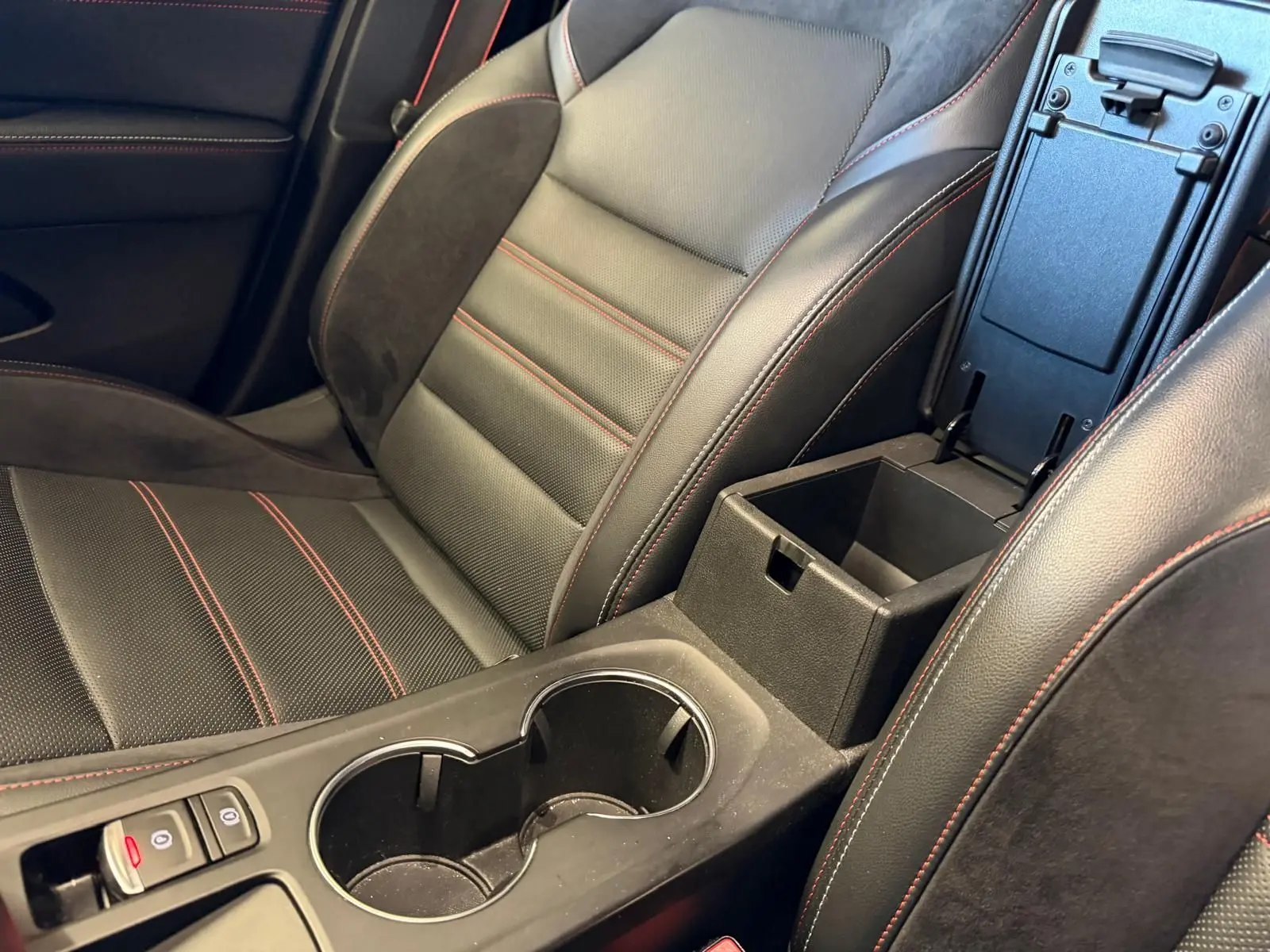 Gros plan sur siège avant noir cuir-suédine avec surpiqûres rouges et accoudoir central ouvert Renault Arkana.