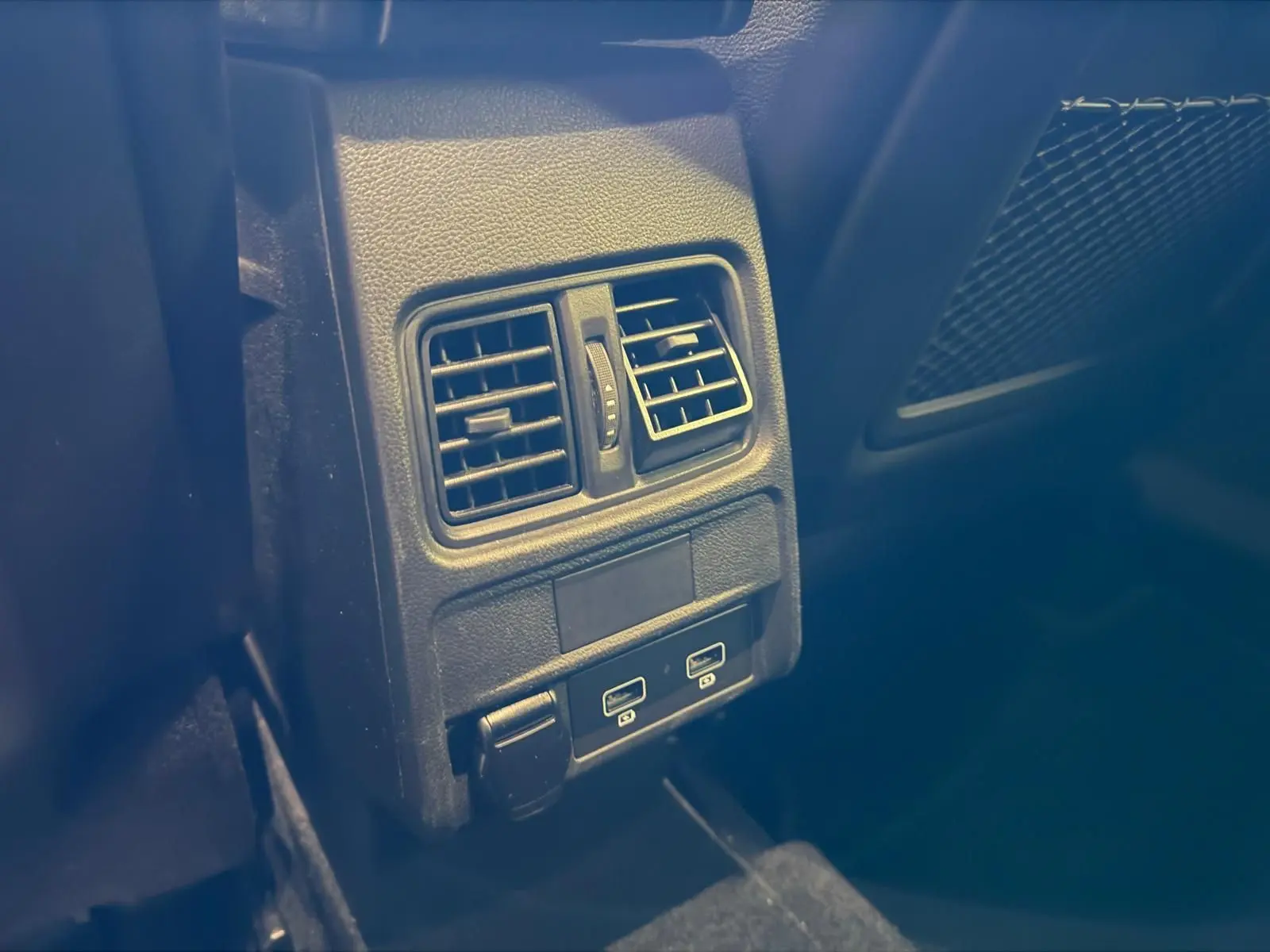 Détail des aérateurs arrière et ports USB dans l'habitacle sombre d'une Renault Arkana blanc nacré.