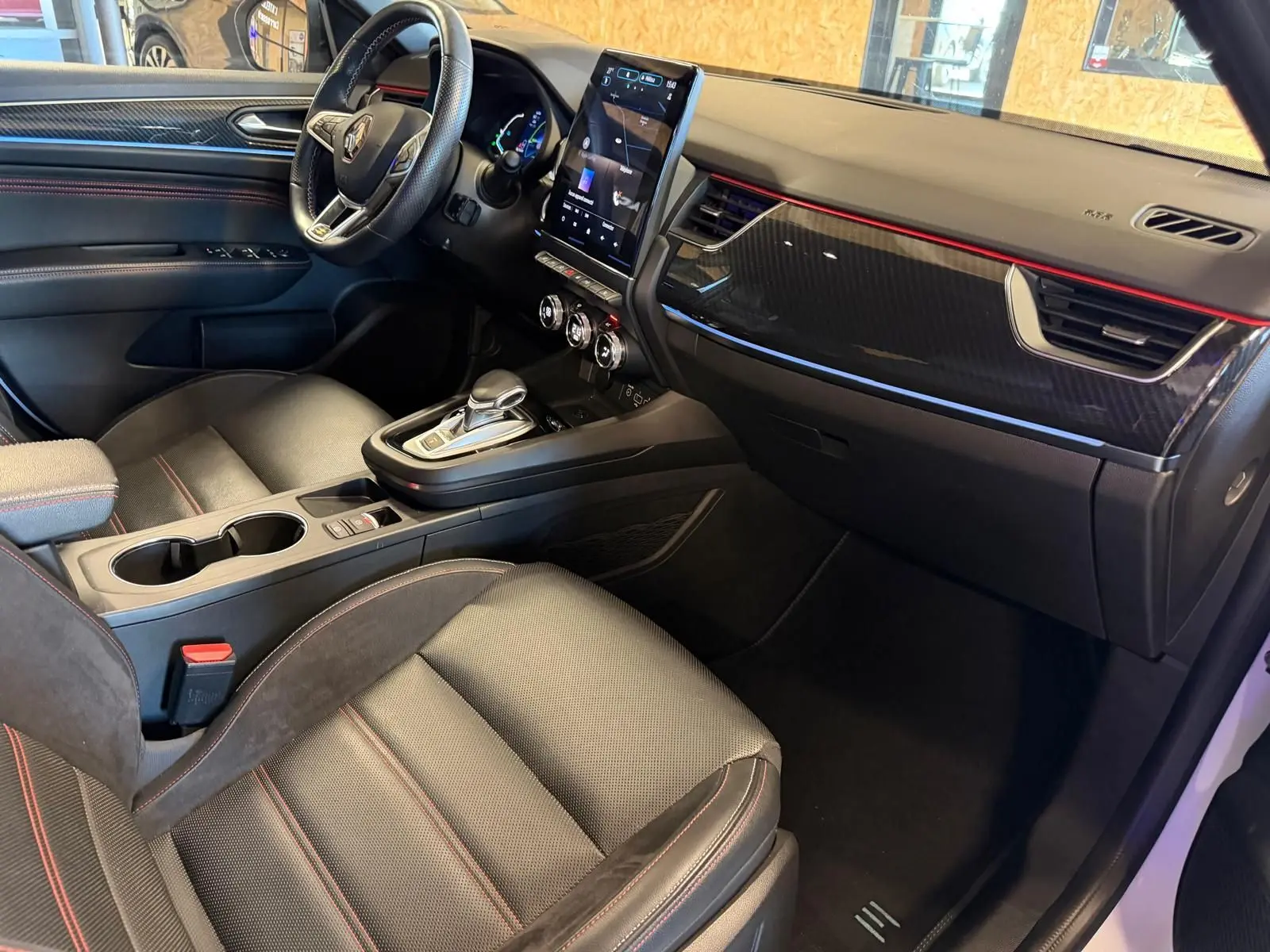 Vue intérieure côté passager du Renault Arkana 1.6 E-Tech hybrid 145 RS Line avec sièges sport noirs et écran tactile vertical.