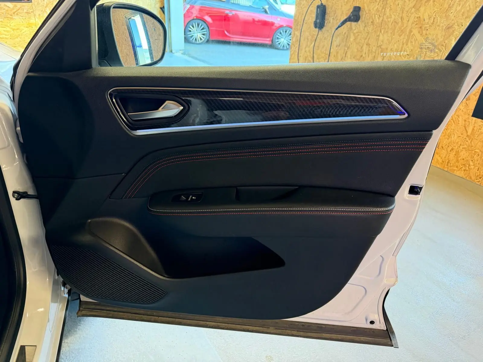 Vue intérieure de la porte avant gauche blanche nacrée du Renault Arkana 1.6 E-Tech hybrid 145 RS LINE avec surpiqûres rouges.