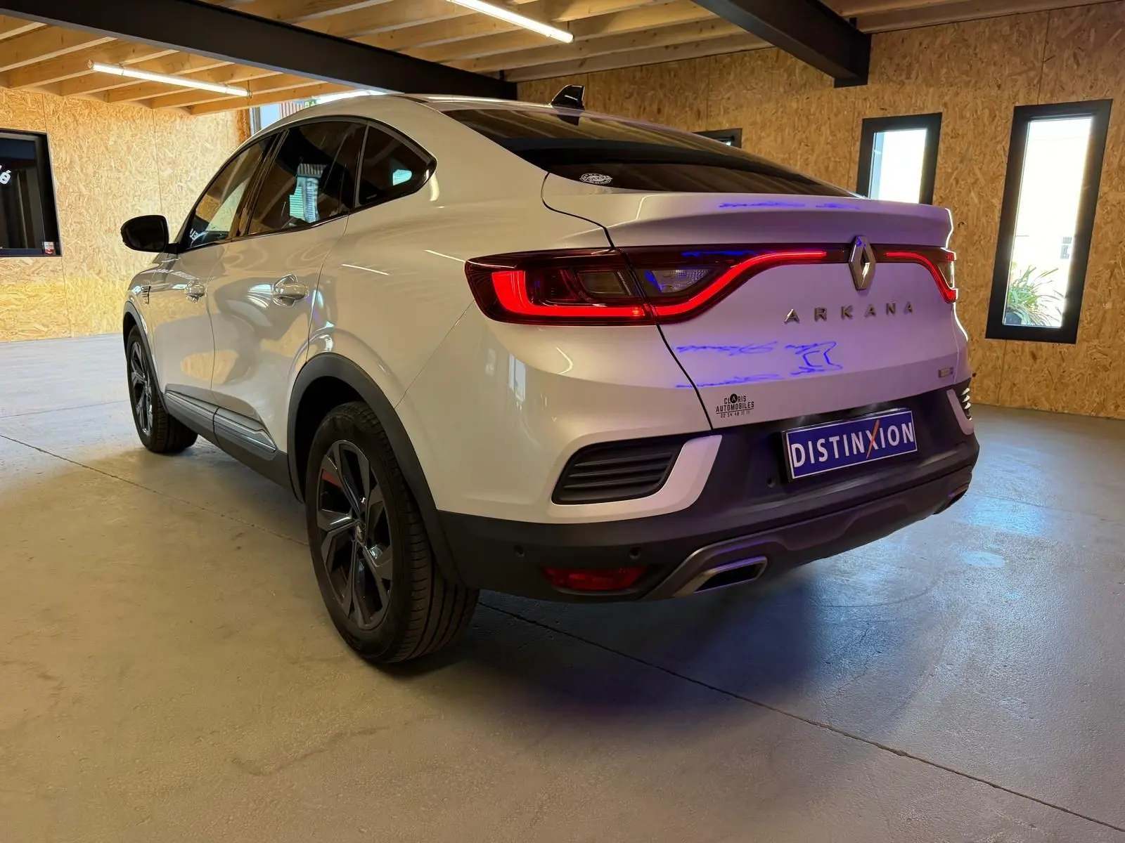 Vue 3/4 arrière droite d'un Renault Arkana blanc nacré avec feux LED et double sortie d'échappement chromée.