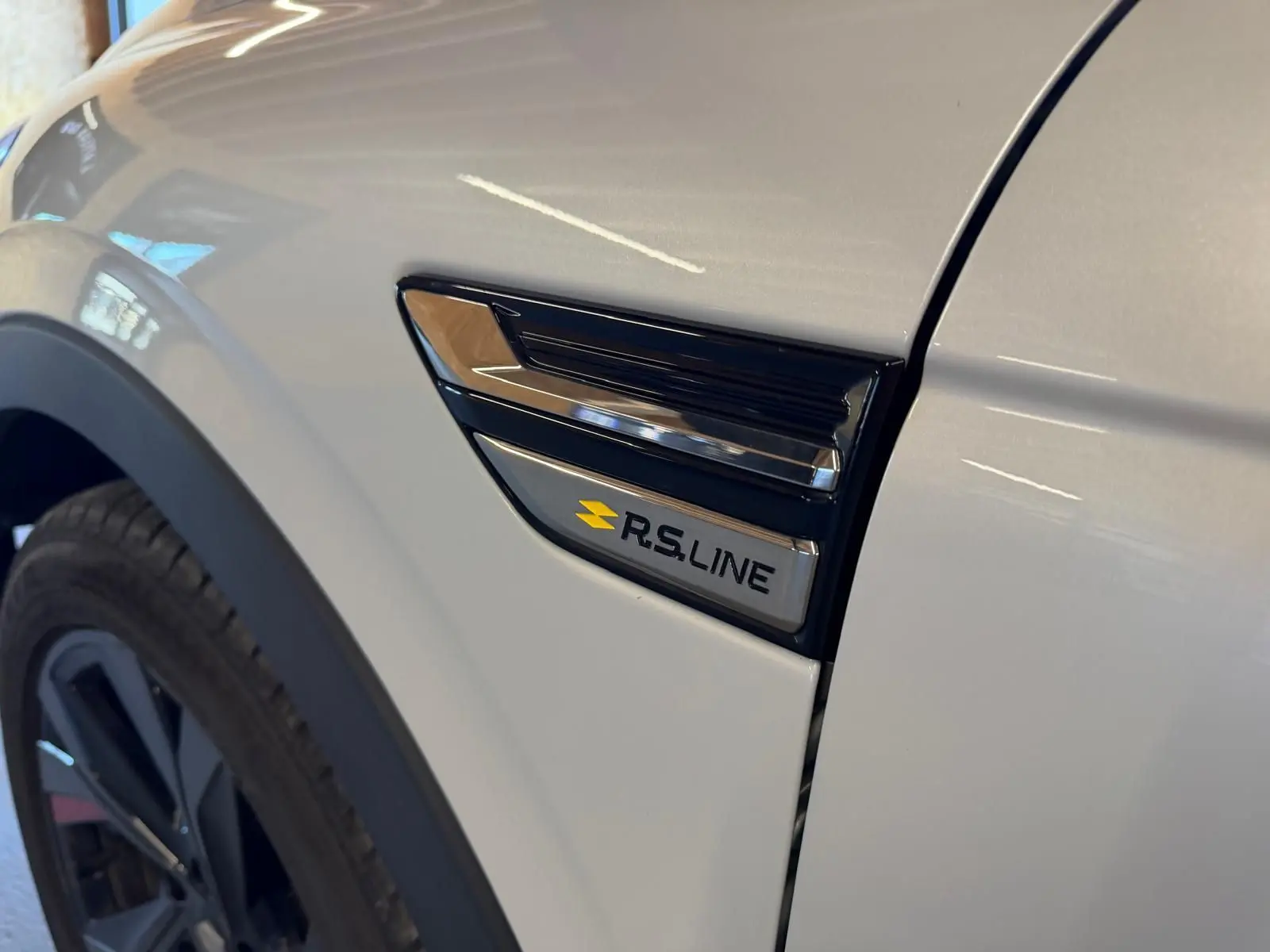 Détail de l'aile avant gauche blanche nacrée du Renault Arkana 1.6 E-Tech hybrid 145 RS LINE avec logo RS LINE.