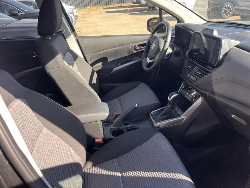 Vue intérieure côté conducteur du Suzuki S-Cross 2024, sièges tissu noir, console centrale avec boîte auto et écran tactile.