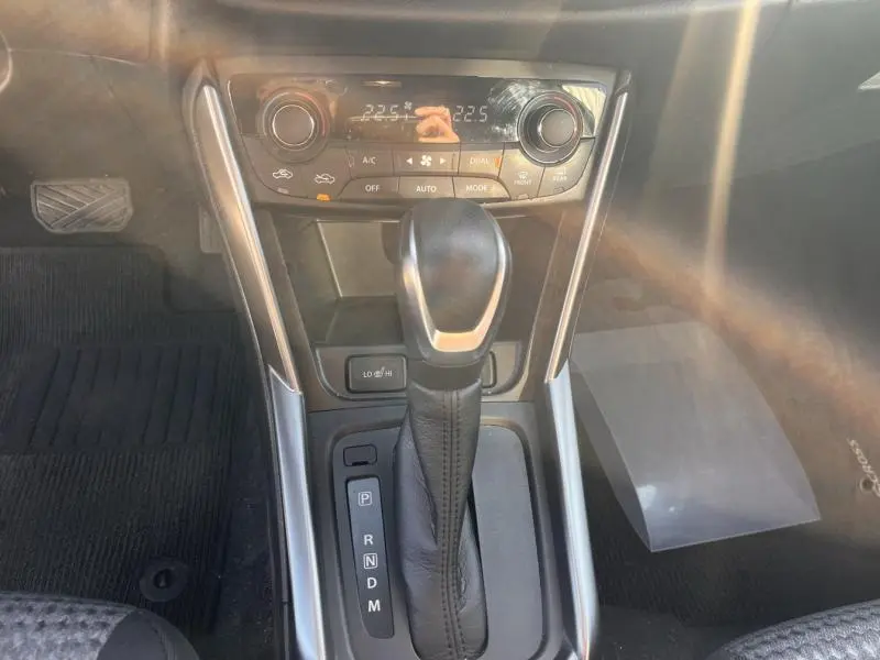 Vue rapprochée de la console centrale du Suzuki S-Cross 2024 avec levier de boîte auto et commandes climatisation.