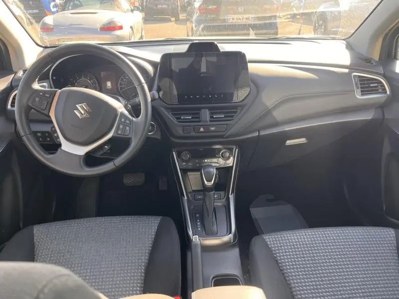 Vue intérieure avant du Suzuki S-Cross 2024, tableau de bord noir avec écran tactile et volant multifonction cuir.