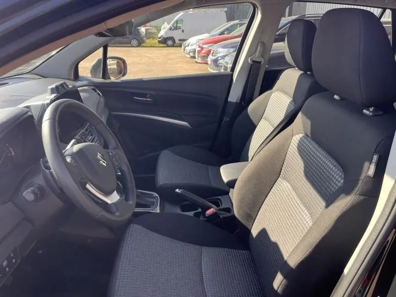 Vue intérieure côté conducteur du Suzuki S-Cross 2024 avec sièges tissu noir et gris et volant multifonction cuir.