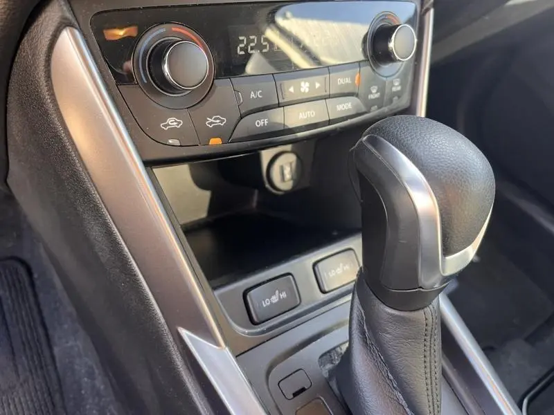 Gros plan sur la console centrale du Suzuki S-Cross 2024, mettant en valeur le levier de vitesse automatique et la commande de climatisation.