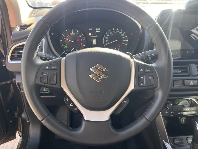 Vue intérieure centrée sur le volant cuir multifonction du Suzuki S-Cross 2024, avec tableau de bord et écran tactile visibles.