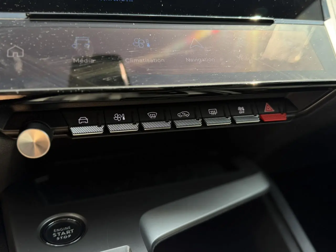 Gros plan sur la console centrale de la Peugeot 308 Hybrid 2025, boutons de commande et écran tactile visibles.