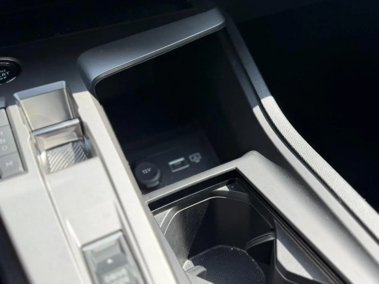 Gros plan sur la console centrale noire du Peugeot 308 Hybrid 145 e-DSC6 Allure avec chargeur induction et bouton start.