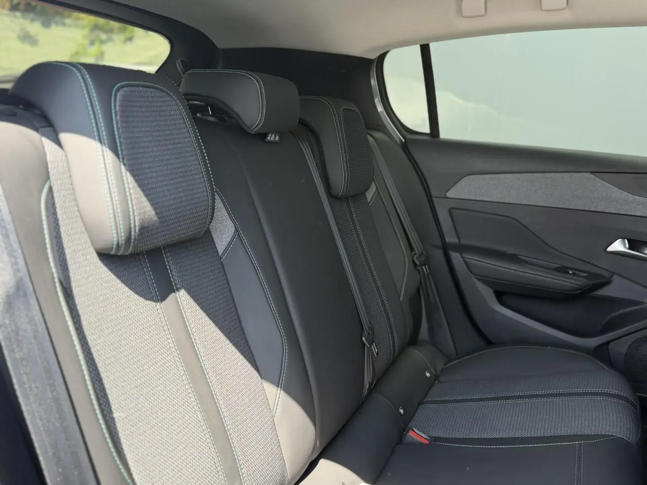 Vue latérale droite des sièges arrière en tissu et TEP noir avec surpiqûres bleues du Peugeot 308 Hybrid 145 Allure 2025.