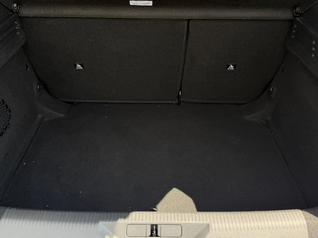 Vue intérieure du coffre noir spacieux de la Peugeot 308 Hybrid 145 e-DSC6 Allure gris Artense, sans chargement visible.