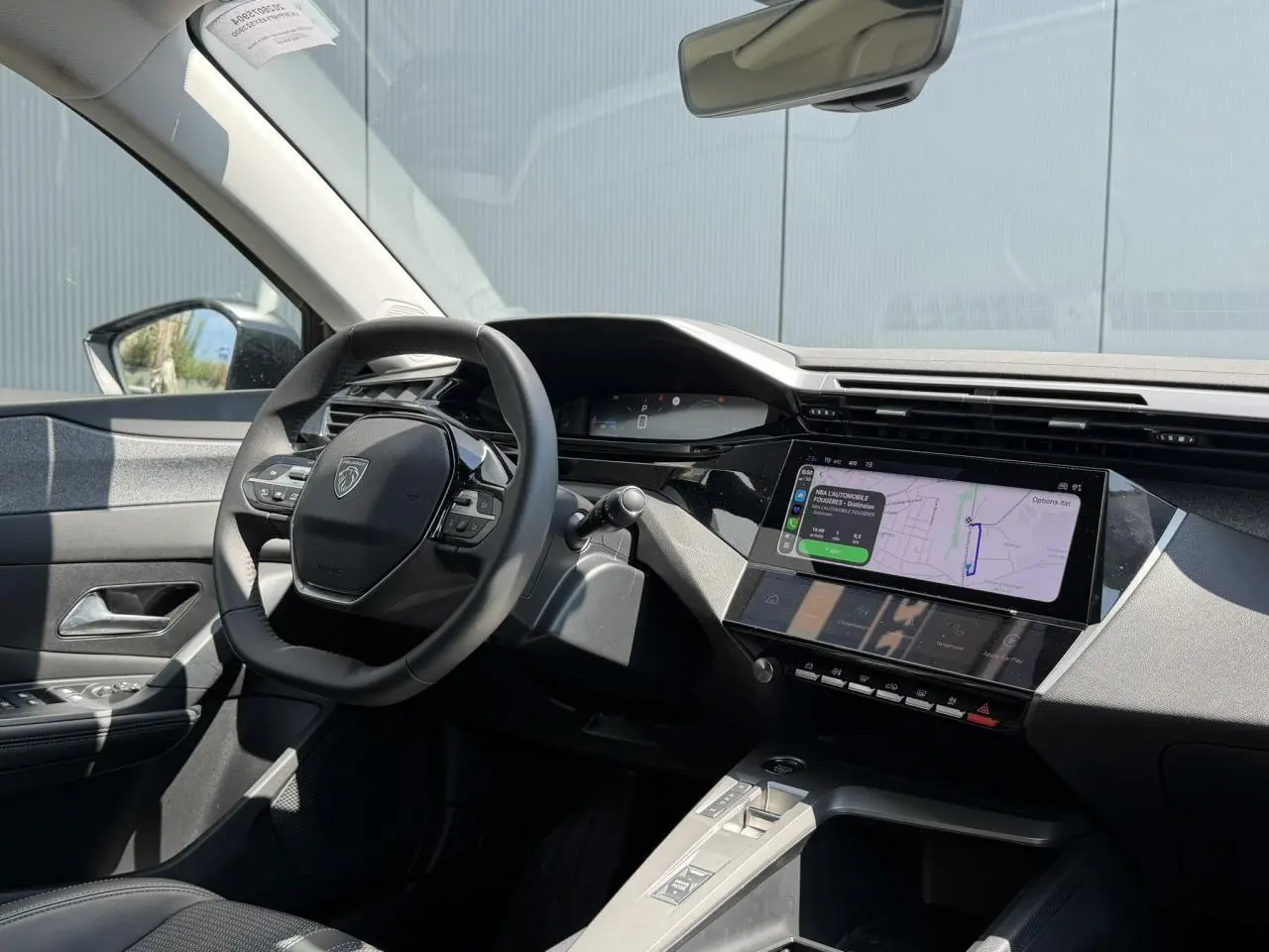 Vue intérieure côté conducteur de la Peugeot 308 Hybrid 2025 avec tableau de bord numérique et écran tactile de navigation.