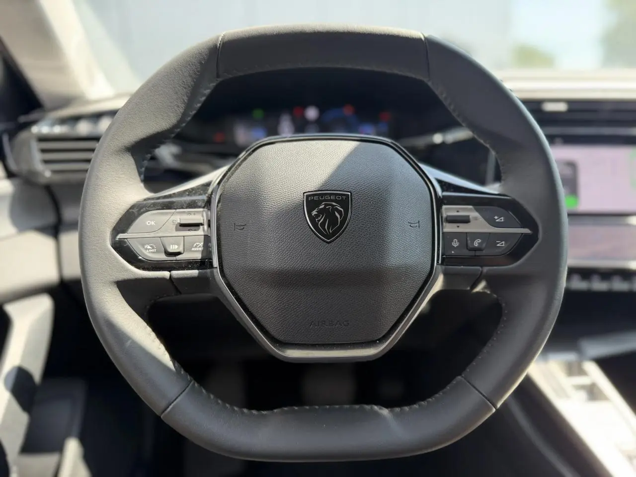 Volant cuir noir au design hexagonal du Peugeot 308 Hybrid 2025, avec commandes intégrées visibles de face.