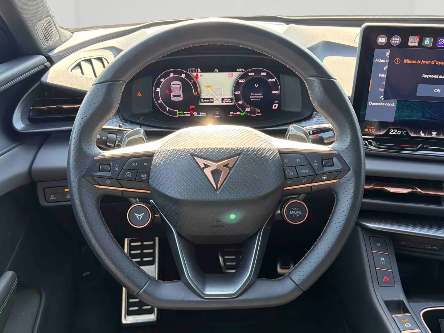 Vue intérieure centrée sur le volant sport cuir noir de la CUPRA TERRAMAR avec tableau de bord numérique et écran tactile.