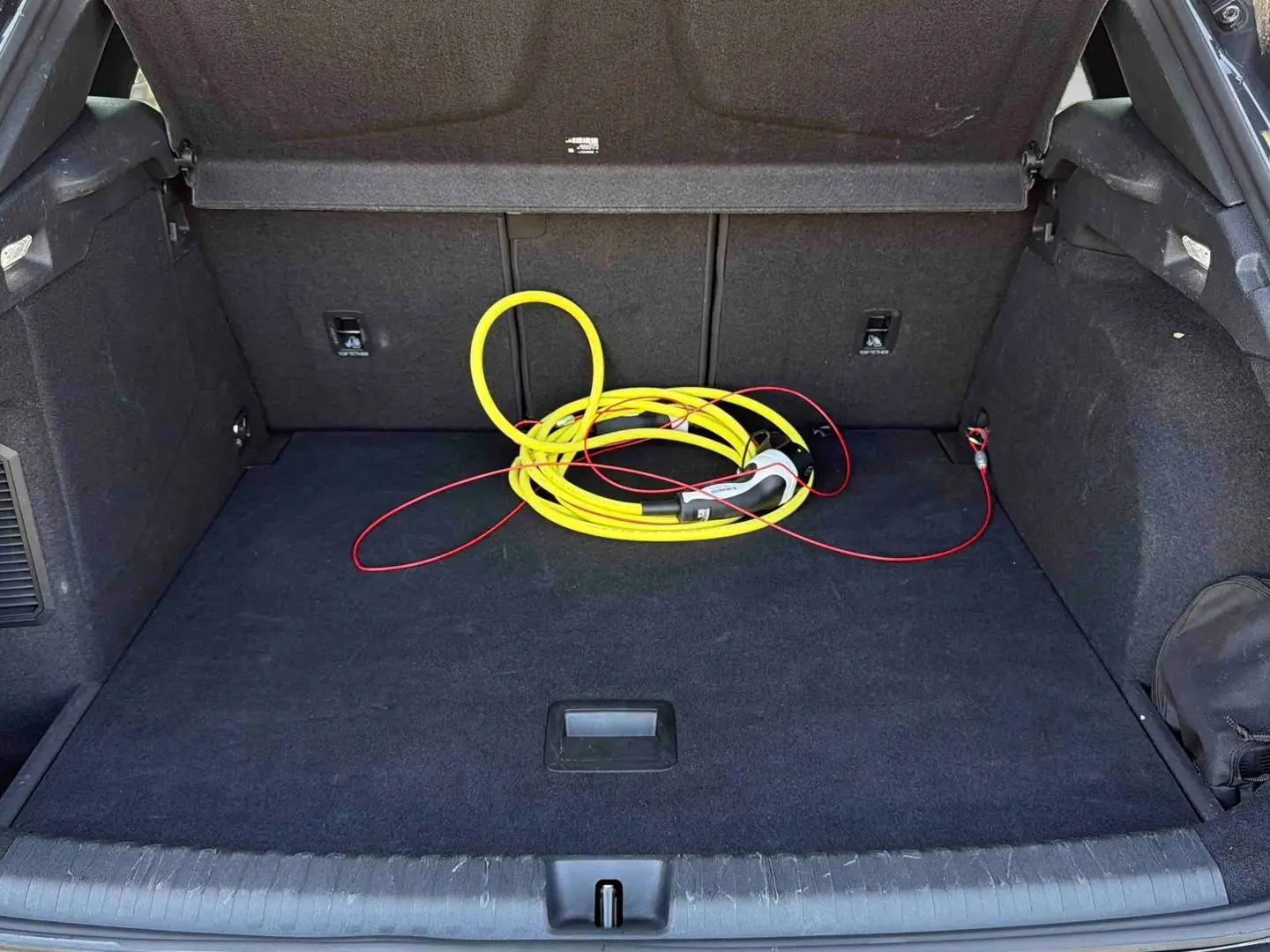 Coffre ouvert d'une CUPRA Terramar gris, vue intérieure montrant un câble de recharge jaune enroulé.