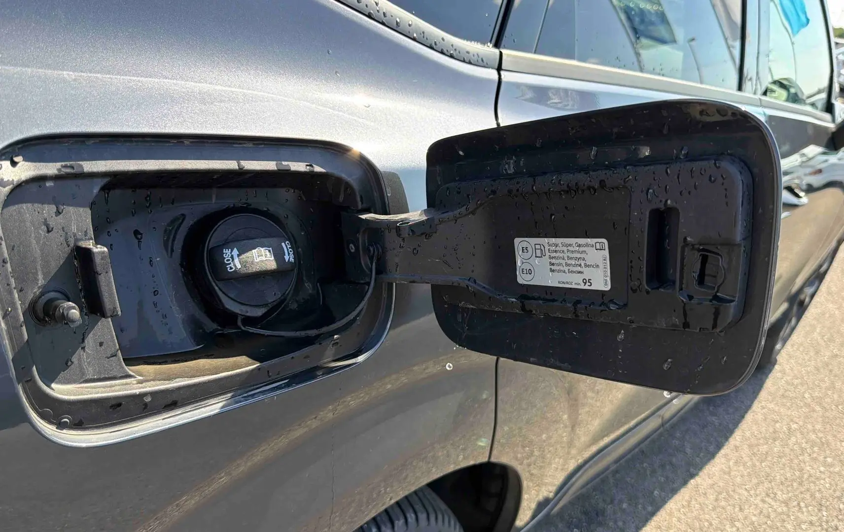 Bouchon de réservoir essence ouvert sur la partie arrière gauche d'une CUPRA TERRAMAR grise sous la lumière du jour.