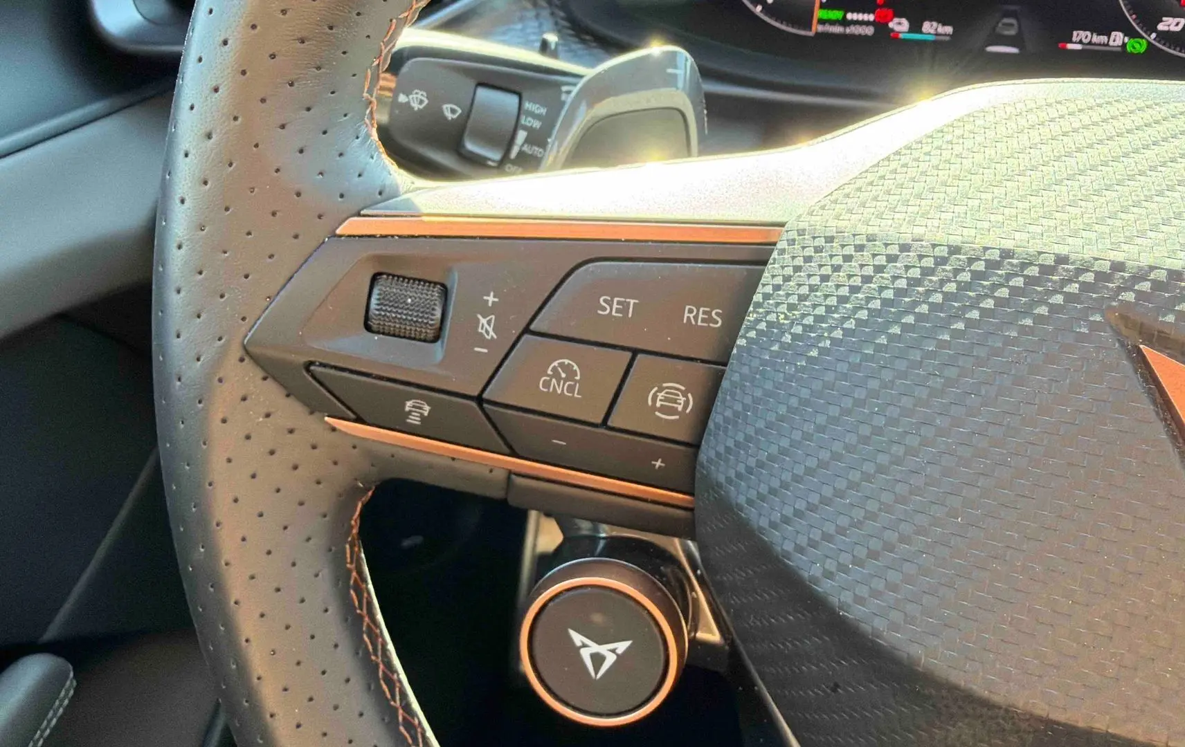 Gros plan sur le volant cuir perforé gris du CUPRA TERRAMAR avec commandes multifonctions et logo orange distinctif.