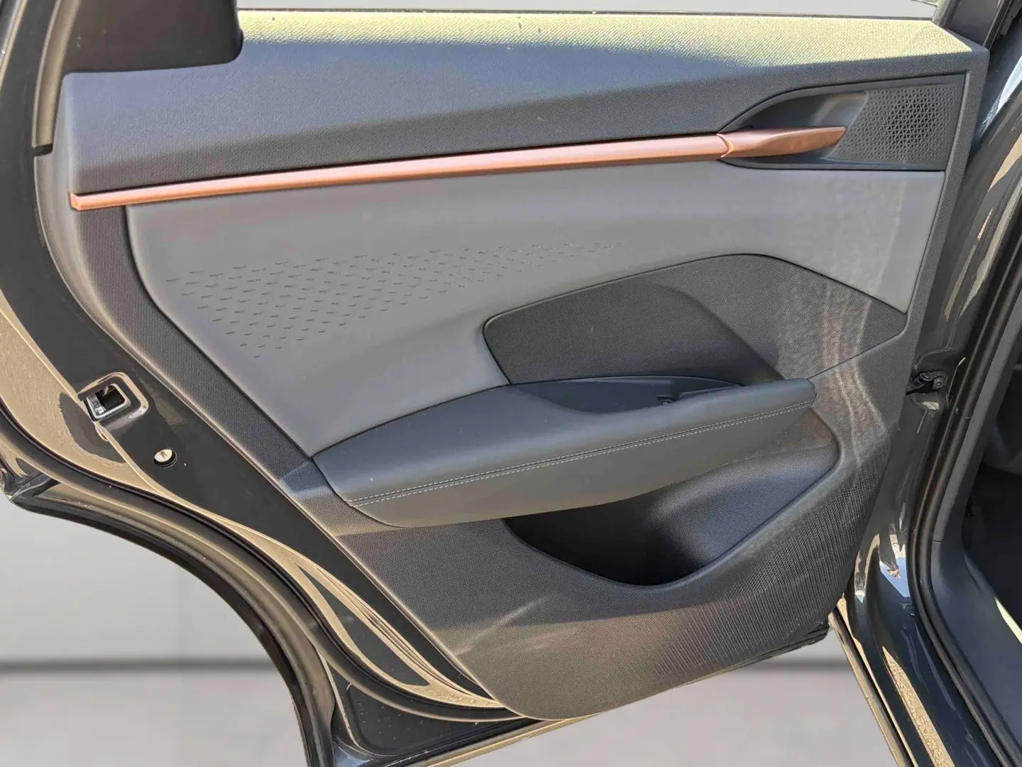 Vue rapprochée de la porte arrière gauche grise du CUPRA TERRAMAR 2025 avec insert décoratif cuivre et habillage tissu et cuir.