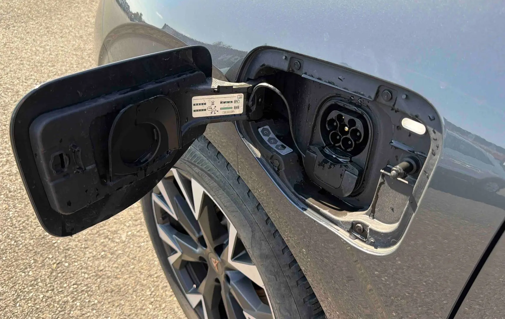 Prise de recharge ouverte sur le côté gauche d’une CUPRA TERRAMAR grise, avec jante anthracite visible.