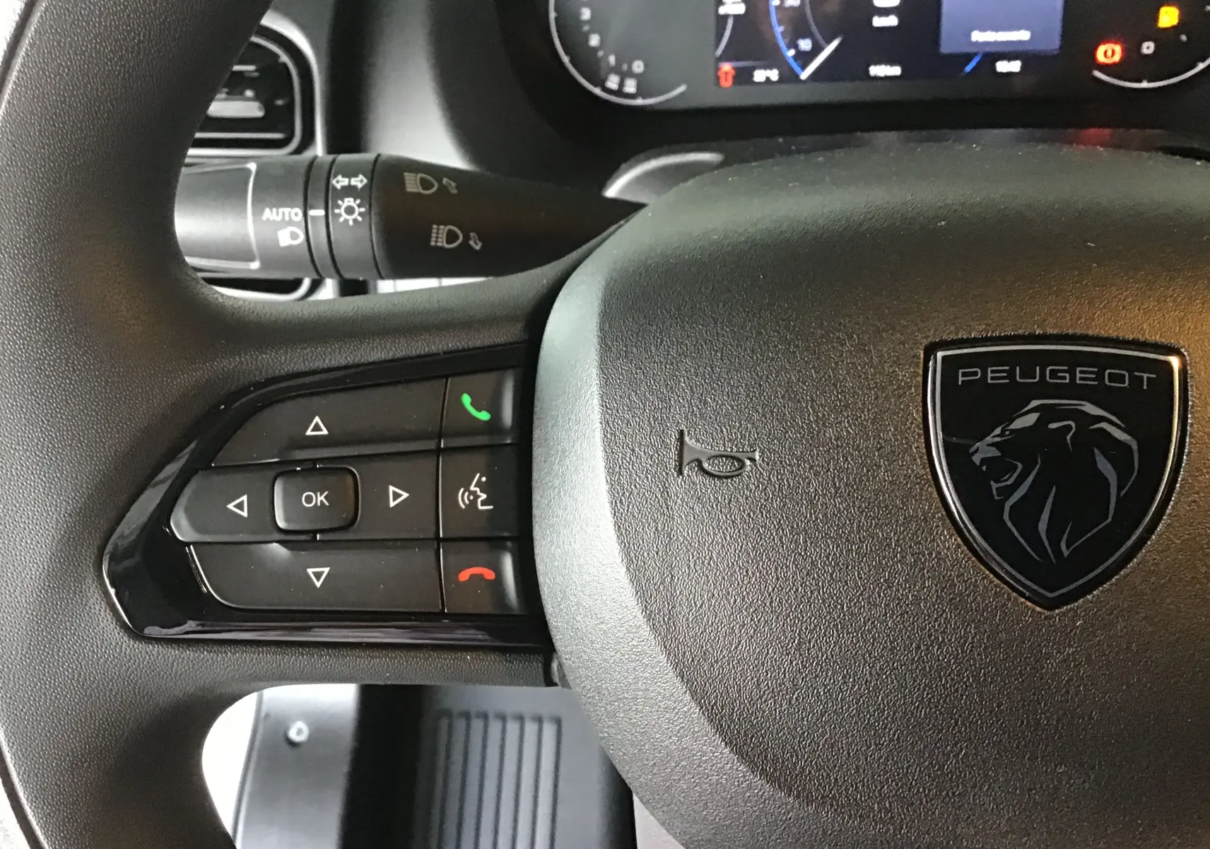 Gros plan sur le volant noir du Peugeot Boxer Fourgon blanc 2025, avec commandes intégrées et logo lion central.