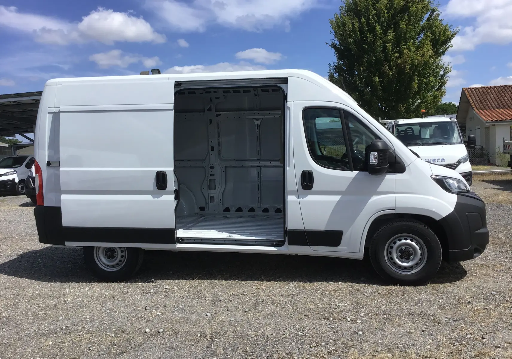 Peugeot Boxer Fourgon blanc vu de profil droit avec porte latérale coulissante ouverte montrant l'intérieur vide.