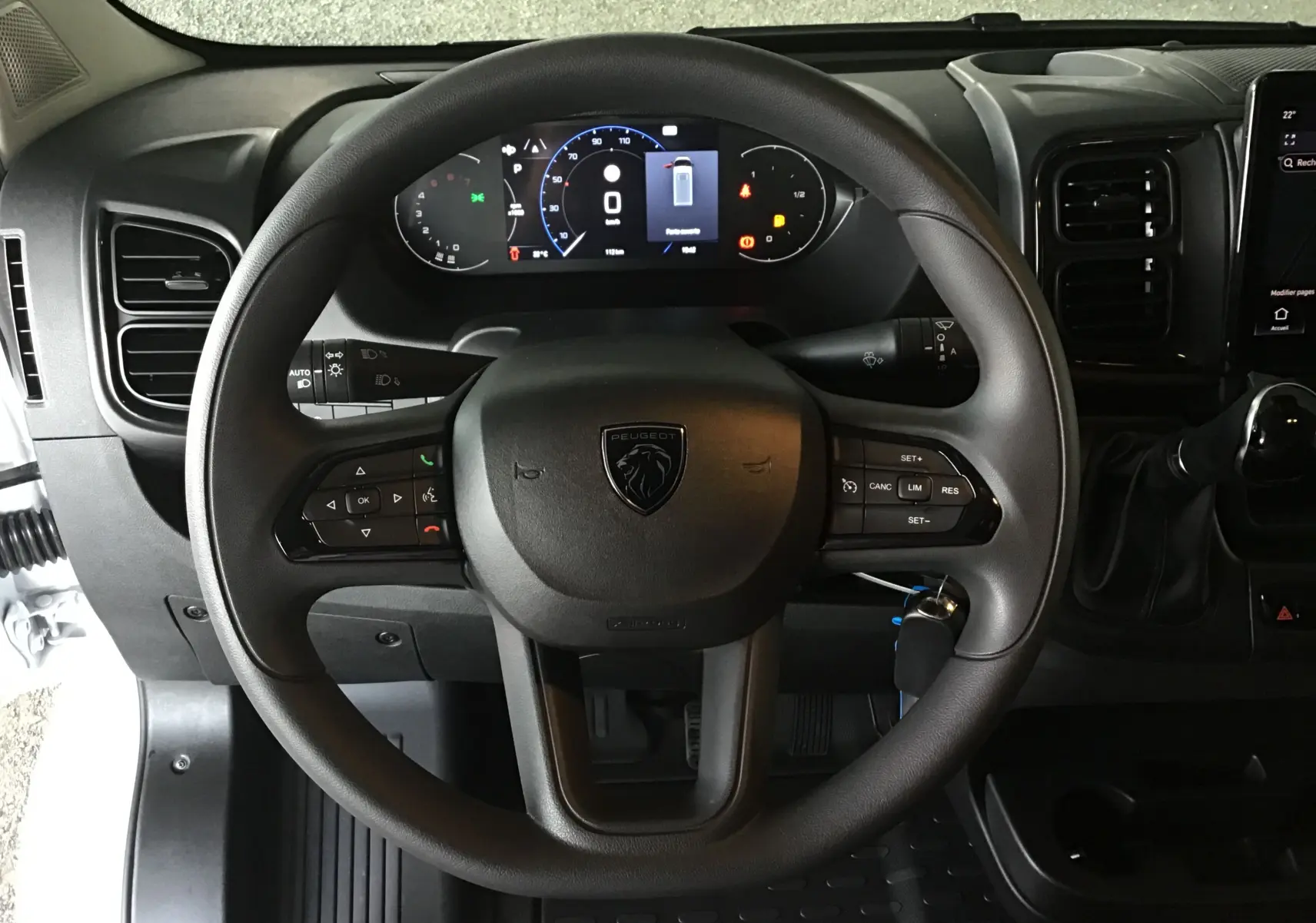 Vue centrée sur le volant noir du Peugeot Boxer Fourgon 2025 avec tableau de bord numérique et commandes intégrées.