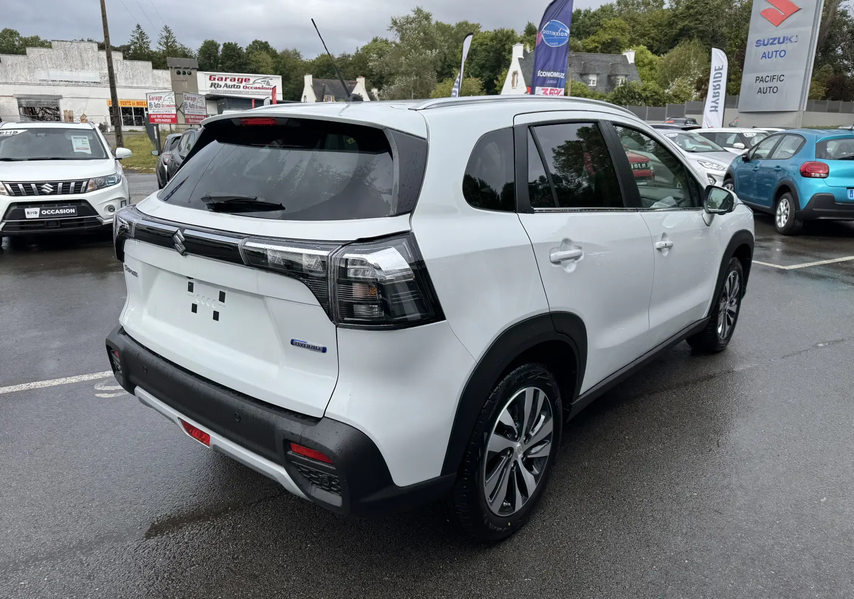 Suzuki S-Cross blanc 2025 en 3/4 arrière droit, avec feux arrière fumés et jantes alliage visibles.