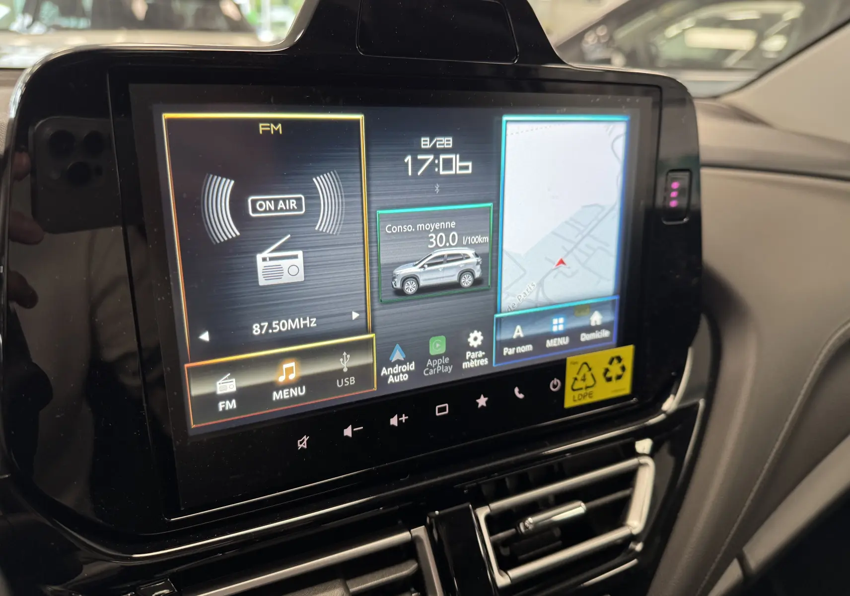 Écran tactile central du Suzuki S-Cross blanc 2025 affichant radio, consommation moyenne et navigation.