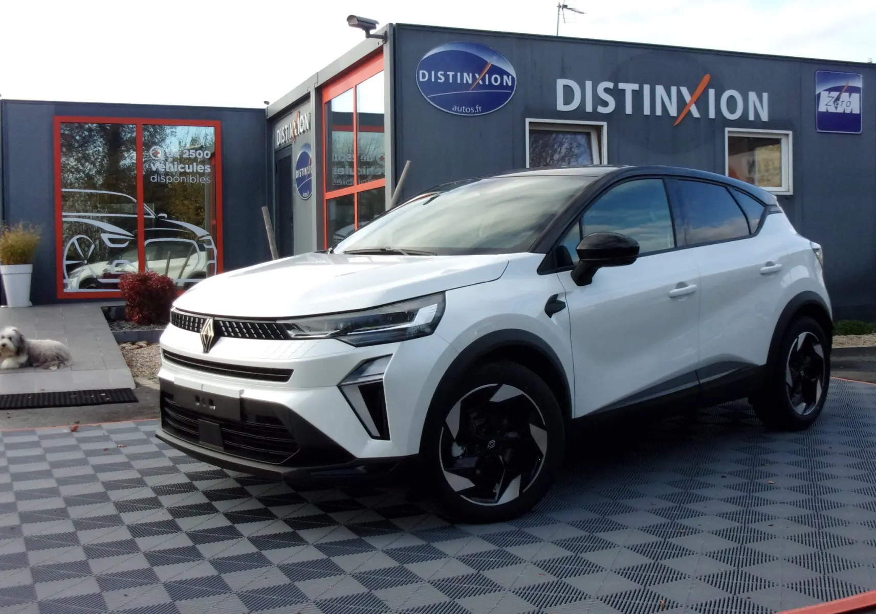 Renault Captur E-Tech blanc nacré vu de 3/4 avant droit sur parking extérieur avec plusieurs véhicules alignés.