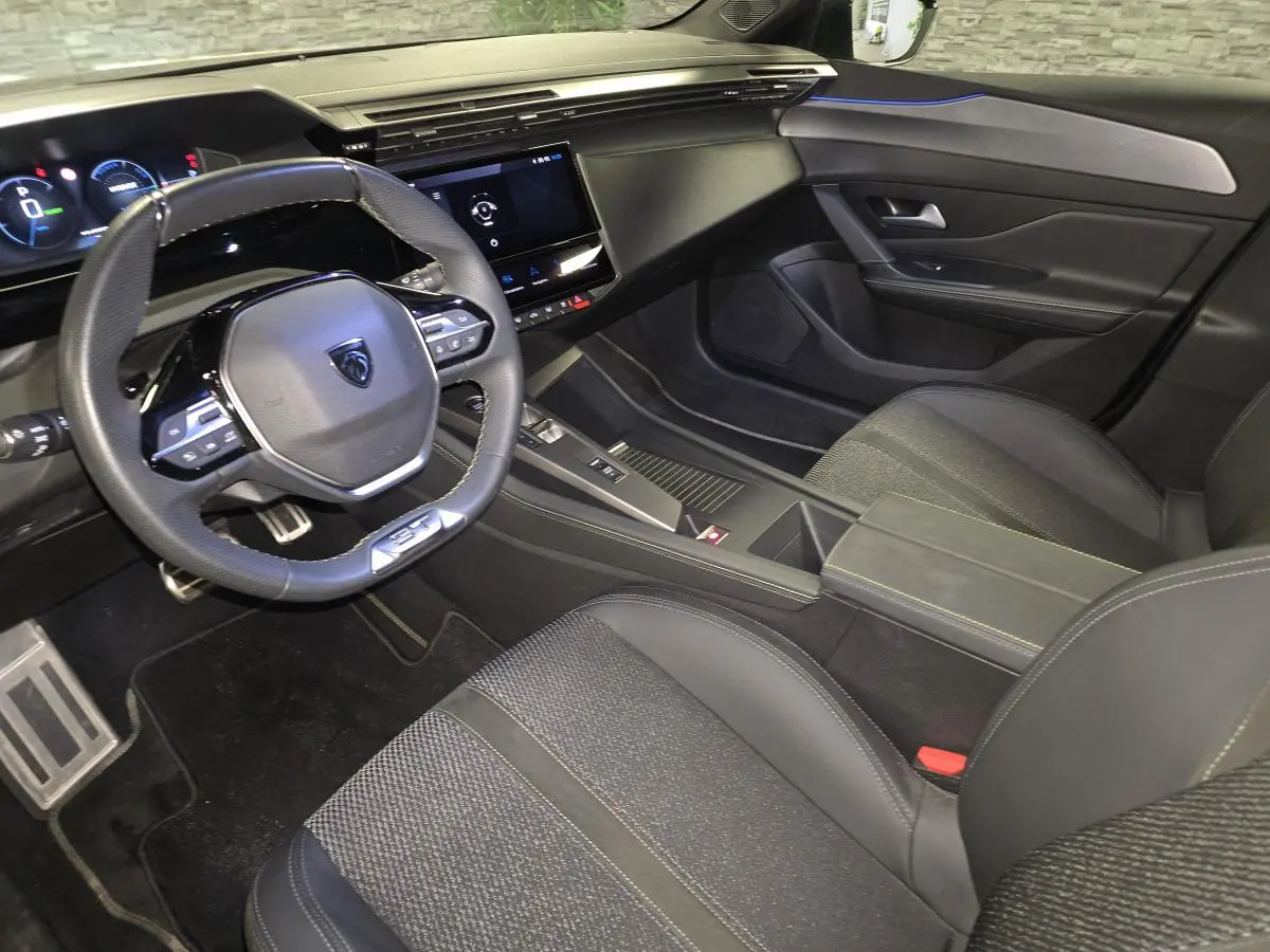 Vue intérieure côté conducteur de la Peugeot 408 gris, avec volant compact, écran tactile et sellerie tissu/TEP noire.