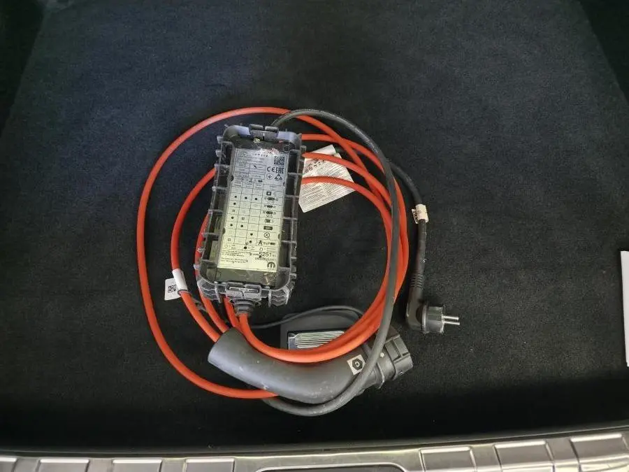 Gros plan sur câble de recharge orange et noir dans le coffre d'une Peugeot 408 gris Selenium 2025 hybride rechargeable.