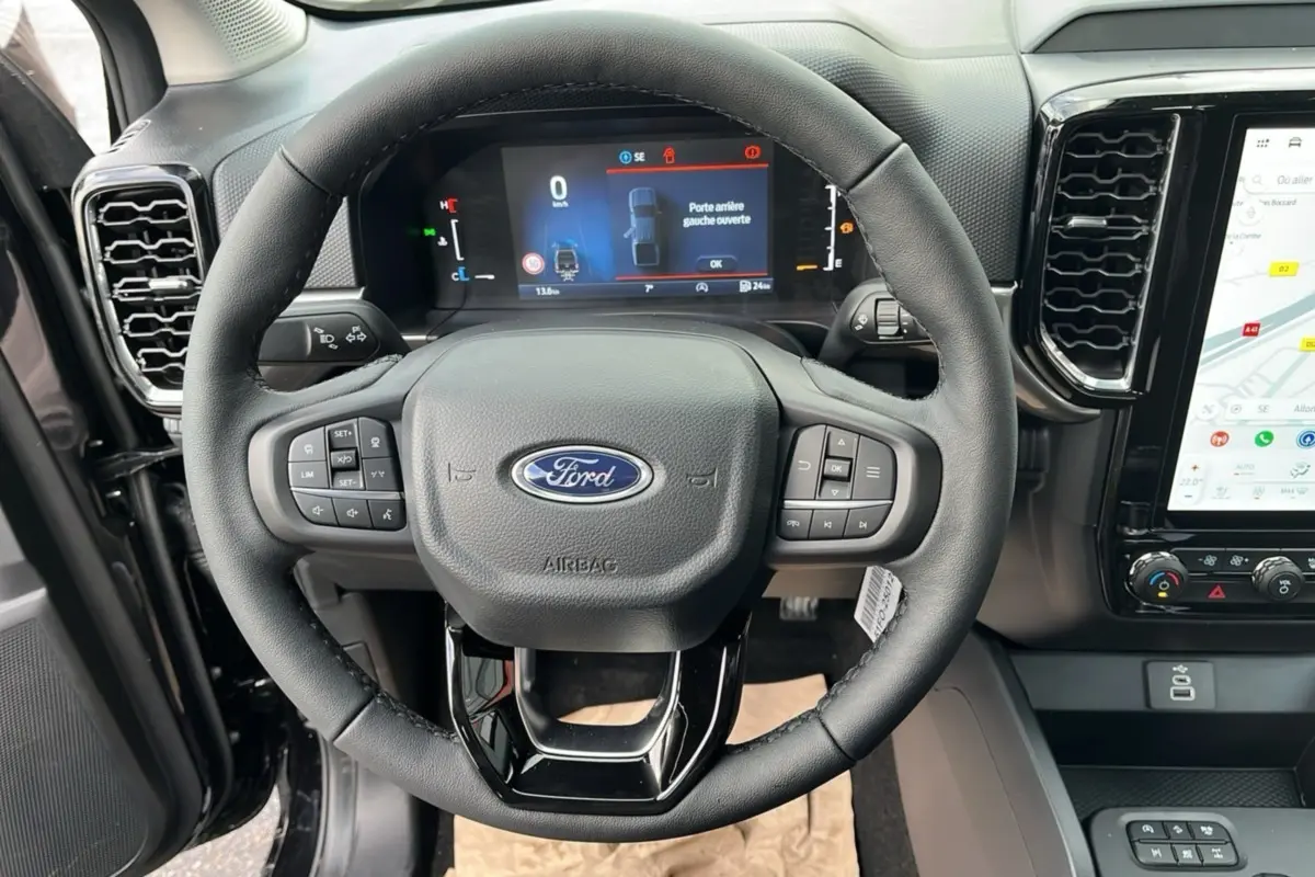 Vue intérieure centrée sur le volant cuir multifonctions du Ford Ranger noir Shadow avec tableau de bord digital et écran tactile.