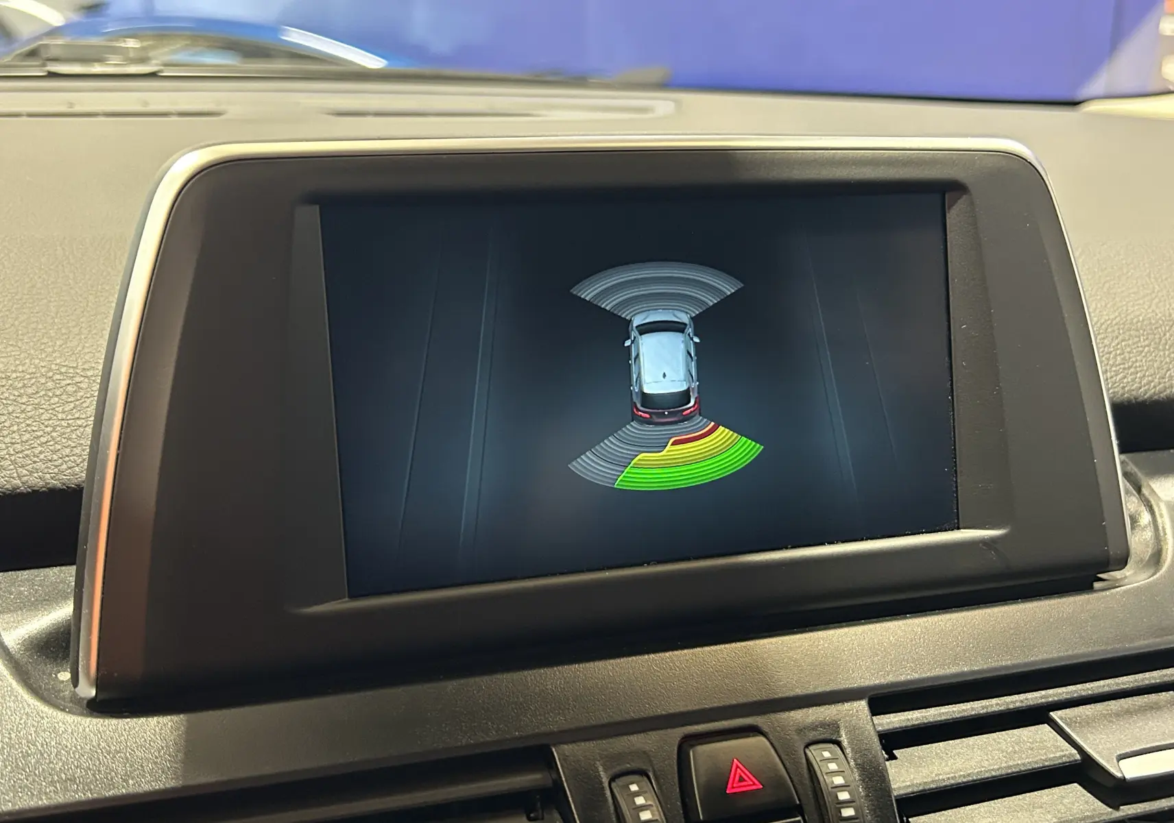 Écran central montrant l'affichage des radars de recul du BMW Série 2 Active Tourer blanc, vue intérieure frontale.