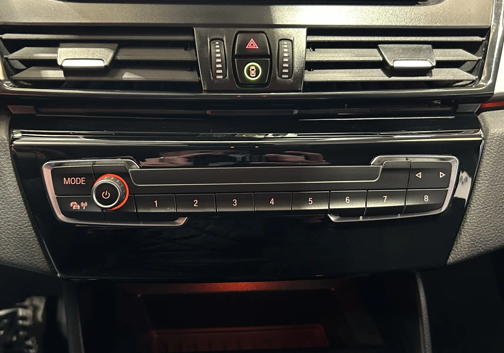 Vue rapprochée de la console centrale noire brillante avec commandes multimédia et ventilation d’une BMW Série 2 Active Tourer blanche.