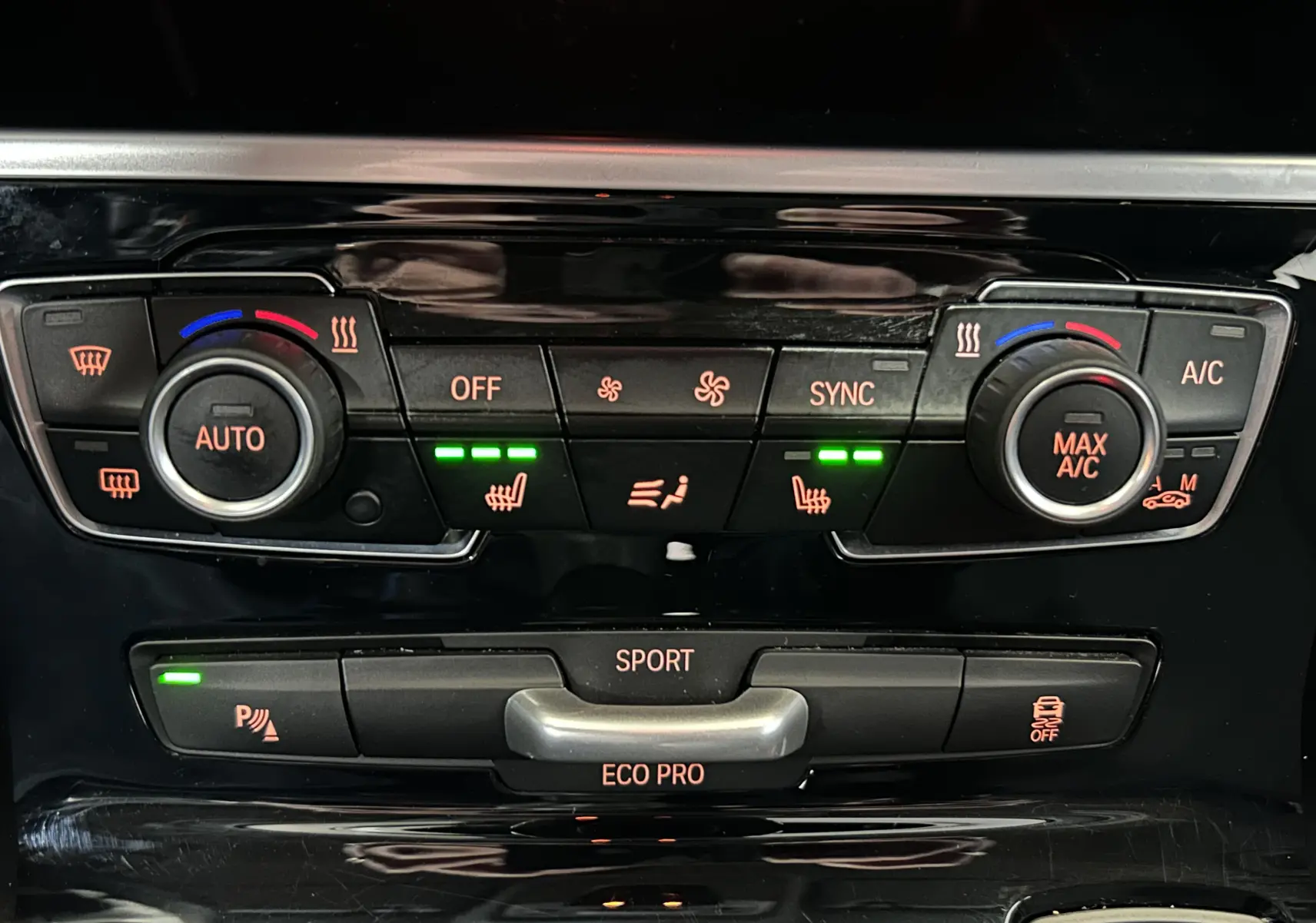 Gros plan sur la console centrale de la BMW Série 2 Active Tourer blanche, montrant les commandes de climatisation et sièges chauffants.