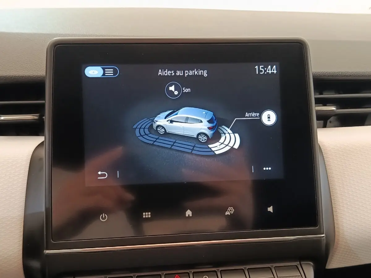 Écran tactile central affichant l'aide au stationnement de la Renault Clio blanche vue de dessus côté droit.
